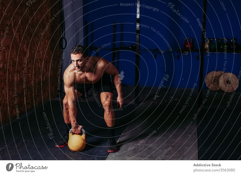 Muscular sportsman exercising with kettlebell in gym exercise swing functional athlete hardwork lift determine male strong heavy muscle center confident fit
