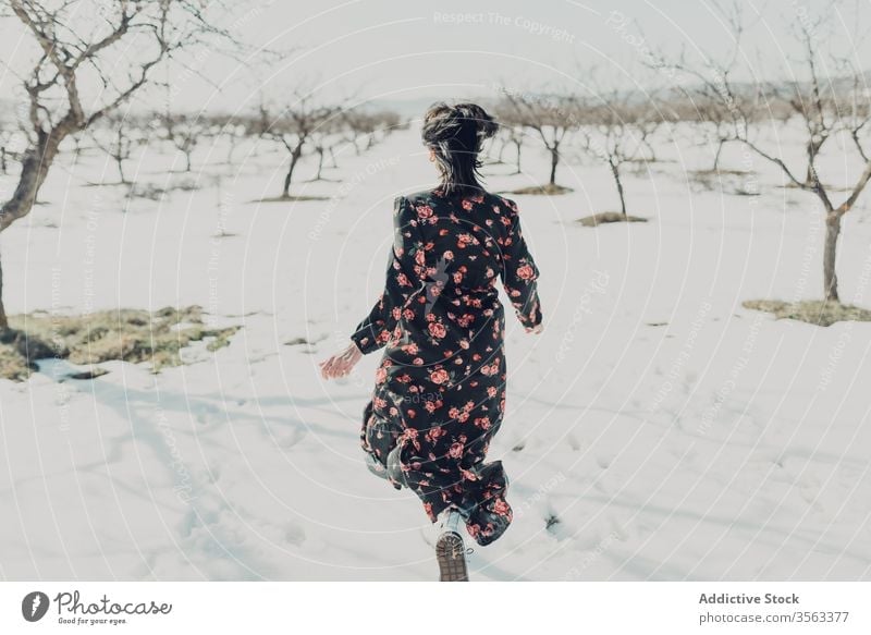 Happy fashionable woman running on snow happy fun winter field cheerful trendy nature style female young joy relax freedom countryside excited carefree playful