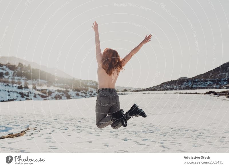 Happy topless woman jumping in snowy field happy carefree nude naked freedom enjoy winter nature energy female fun countryside cheerful young active adventure
