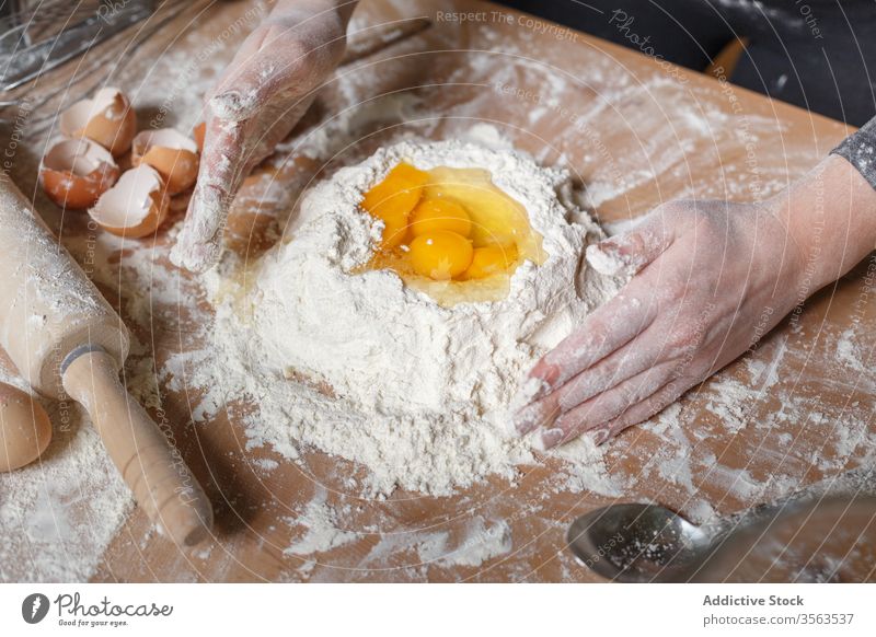 Crop cook preparing dough on table flour add egg mix recess prepare food pastry gastronomy kitchen ingredient person hand cuisine culinary homemade recipe meal