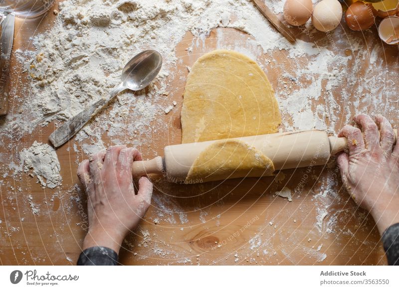 Crop lady rolling dough with rolling pin on table cook woman pastry elastic flour egg kitchenware jug eggshell glass prepare ingredient process pasta utensil