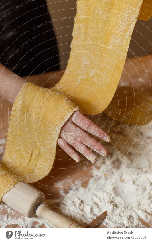 Faceless woman with rolled dough in kitchen elastic pasta homemade cook flour raw kitchenware dish egg prepare ingredient process rolling pin table utensil food
