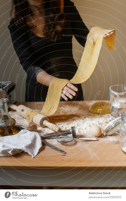 Faceless woman with rolled dough in kitchen elastic pasta homemade cook flour raw kitchenware dish egg prepare ingredient process rolling pin table utensil food