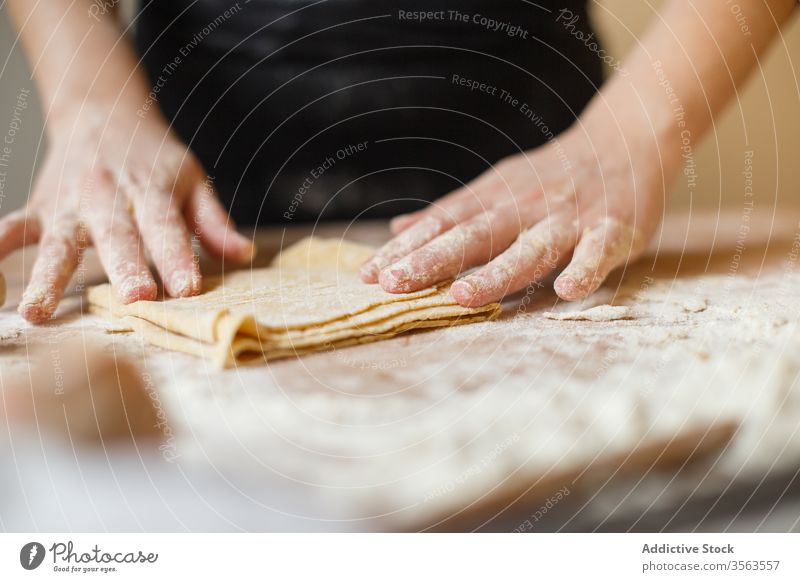 Crop person preparing making pasta with elastic dough fold layer cook roll flour prepare kitchen ingredient process table utensil food cuisine culinary homemade