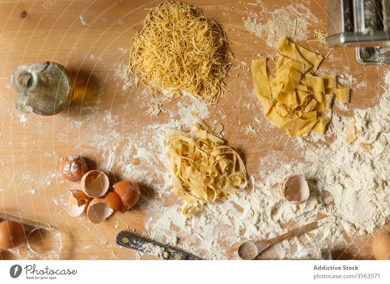 Composition of pasta and kitchenware on table raw flour utensil eggshell olive oil various shape dough pastry messy make device cookery prepare food spoon