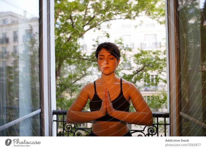 Calm standing in prayer pose on balcony in summer woman yoga peace harmony home relax eyes closed healthy lifestyle vitality wellness meditate athlete tadasana