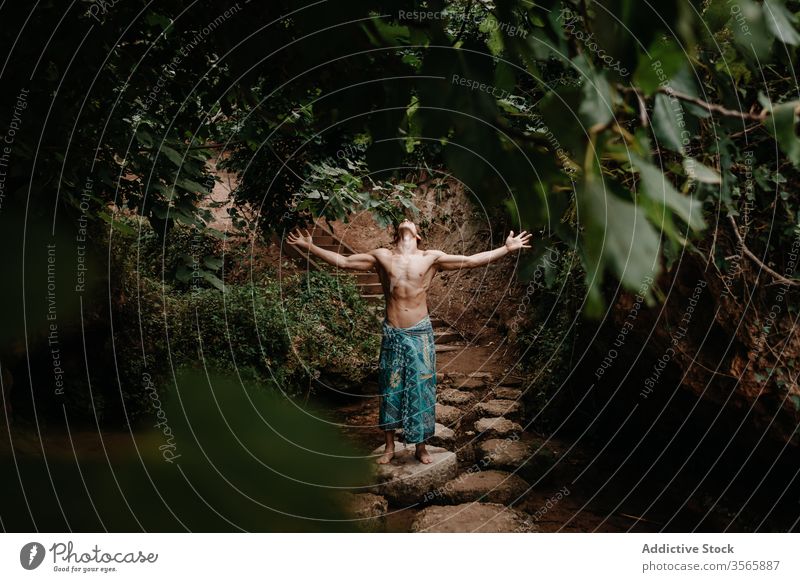 Unrecognizable man in traditional pants meditating in forest meditate spirit nature ethnic tree garden shirtless male muscular naked torso barefoot harmony