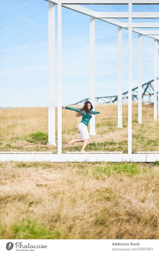Young woman dancing near metal construction in countryside field dance fall bend geometry fly modern street art nature harmony calm female creative dancer