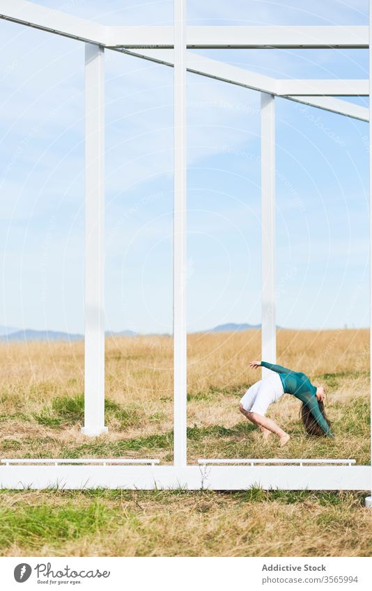 Young woman near metal construction in countryside field dance fall bend geometry fly modern street art nature harmony calm female creative contemporary frame