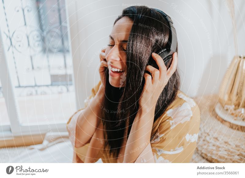 Happy woman with headphones listening music at home room singing chill happy enjoy comfort lounge bedroom relax lifestyle rest gadget device young cozy