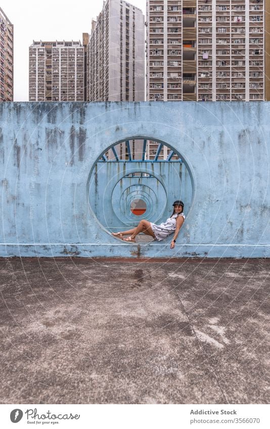 Woman sitting near walls with tunnel in Hong Kong woman passage street installation city unusual creative summer female shek kip mei hong kong round shape