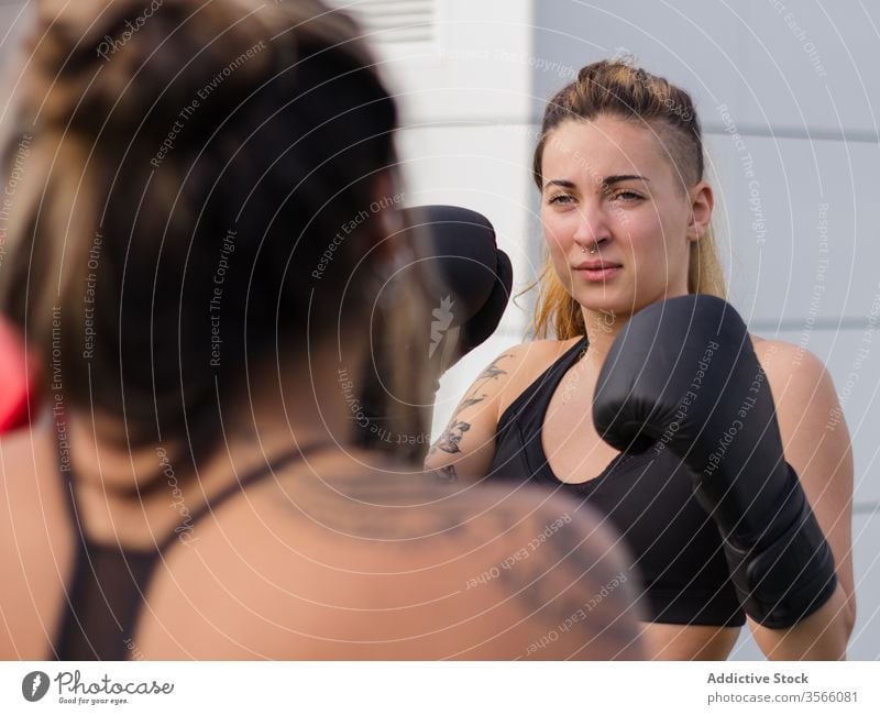 Determined female boxer training on street boxing glove sportswomen fighter punch workout determine fit sports ground active wear athlete body brutal attach