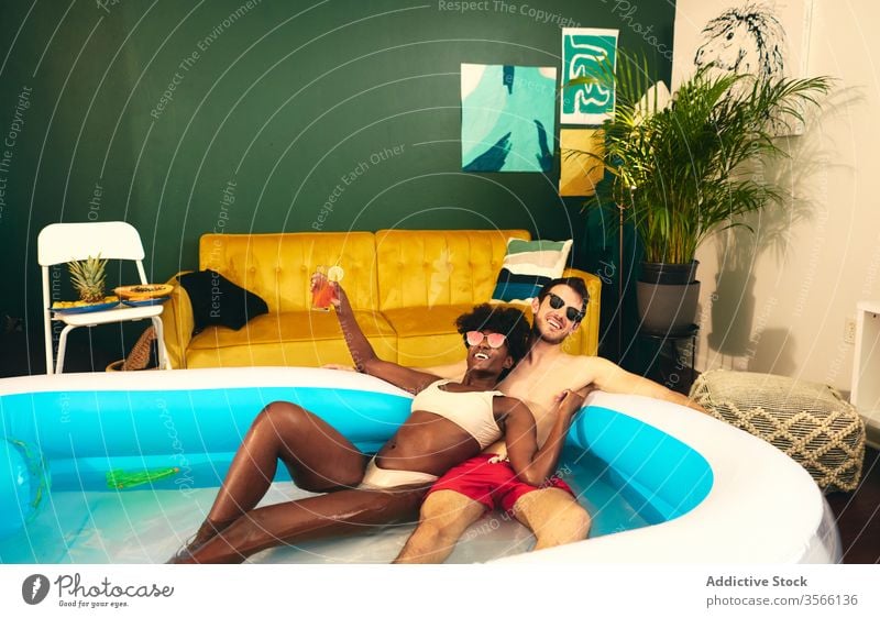 Content multiethnic couple resting in inflatable pool party stay at home content having fun self isolation in love social distancing water together multiracial