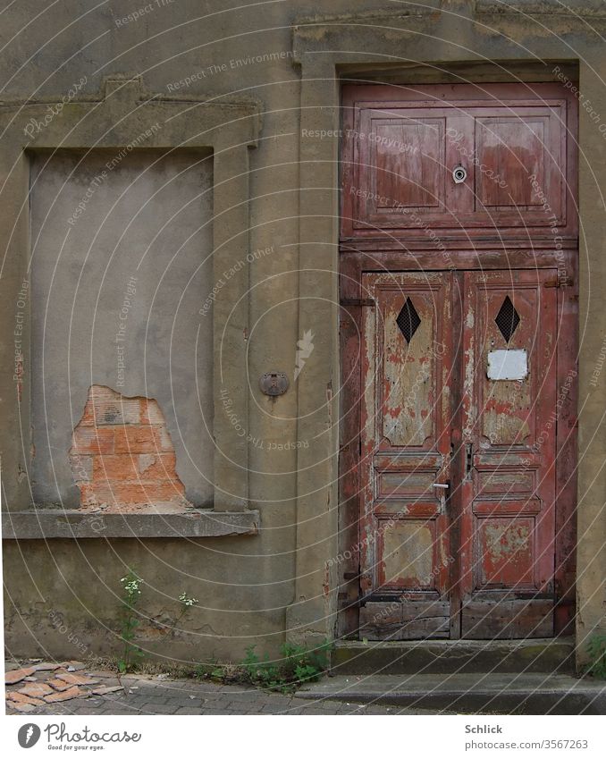 Facade antique wooden front door with empty shield and bricked up window Old window opening too sign Empty Copy Space plants bailer dilapidated Door frame