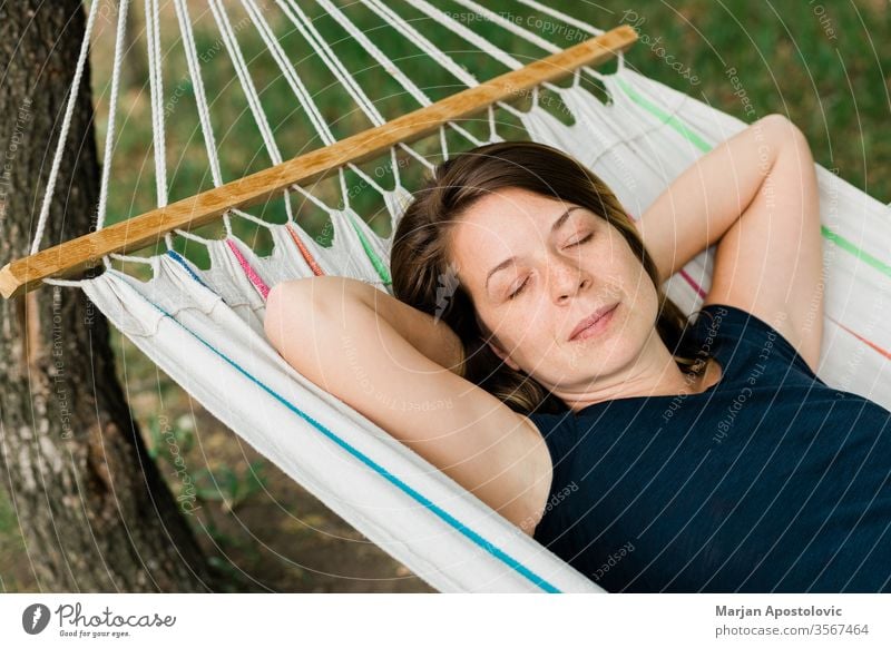 Young woman relaxing in the hammock in nature adult alone backyard calm carefree casual comfortable countryside day dream easy enjoy female forest furniture