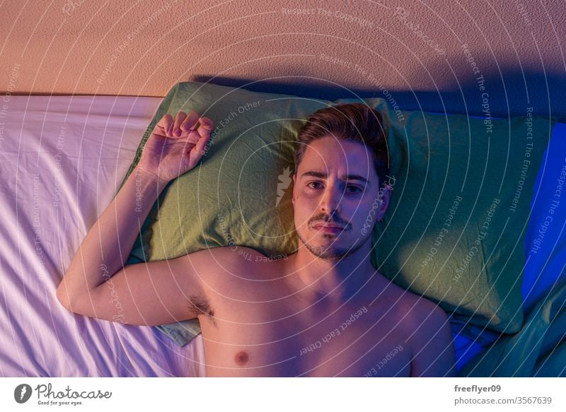 Portrait of a man on the bed from above at night portrait male quarantine depression pillow naked nude coronavirus covid-19 isolation self-isolated insomnia
