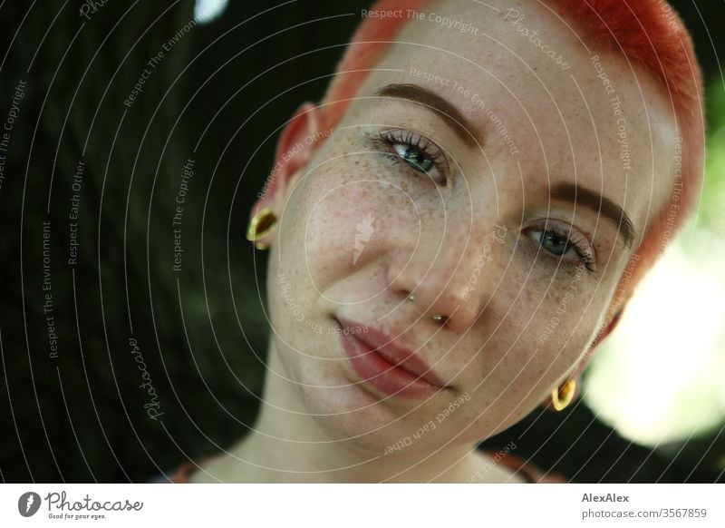 Portrait of a young woman in front of a tree Woman 18-25 years already Slim Freckles Red-haired Jewellery Piercing tattooing Face Fair-skinned Short-haired