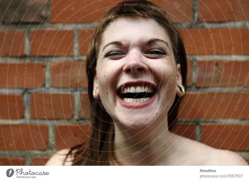 Portrait of a laughing young woman in front of a brick wall Woman Youth (Young adults) already Strong Alternative great Piercing Skin Intensive Looking look