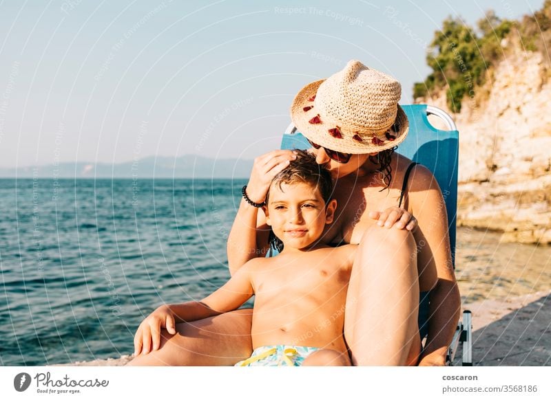 Mother and son relaxing on the coast near the sea beach boy caucasian child childhood coastline day enjoying enjoyment exotic family fun hammock happiness happy