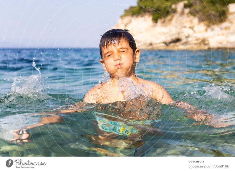 Little kid having fun into the sea active baby beach beautiful blue boy caucasian child childhood cute drops dynamic energy face happiness happy happy kids