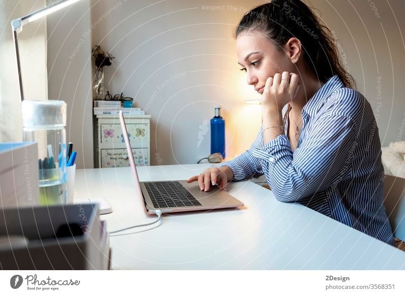 Side view of a young woman working at home with laptop person business businesswoman computer technology adult studying office indoor side view female sitting
