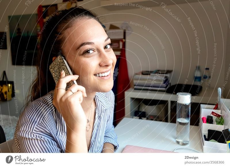 Smiling woman having a phone call at home smiling communication adult person desk mobile phone technology business indoor sitting smartphone computer desktop
