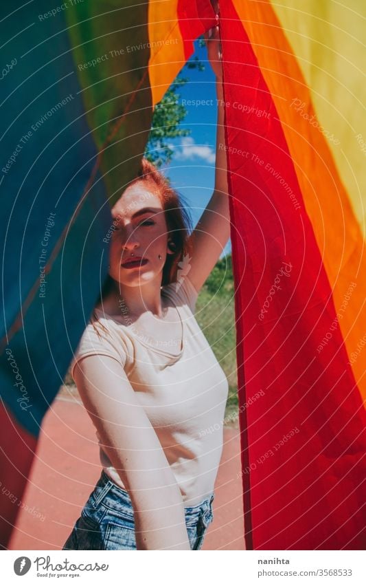 Young woman covering by a rainbow flag lgbti gay pride party rain bow homosexual lesbian color colorful outdoor social issue gender equality society free