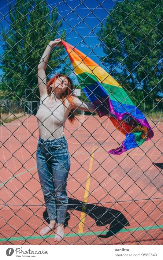 Young redhead woman celebrating gay pride day lgbti party flag rain bow homosexual lesbian color colorful outdoor social issue gender equality society free