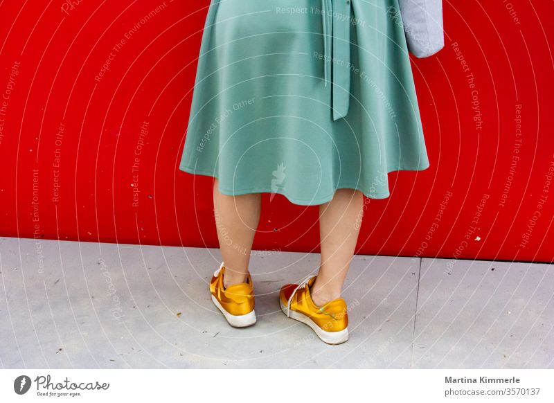 Lady with golden sneakers and green skirt in front of red wall more adult Attractive Bag Blue casually garments Dress Fashion Footwear luck fortunate lifestyle