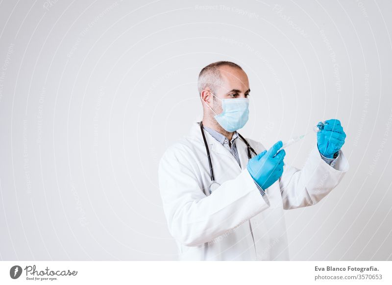 doctor man using a syringe and a vial. using protective mask and gloves during corona virus covid 2019 pandemic. Health care and medical concept cod-2019 tube