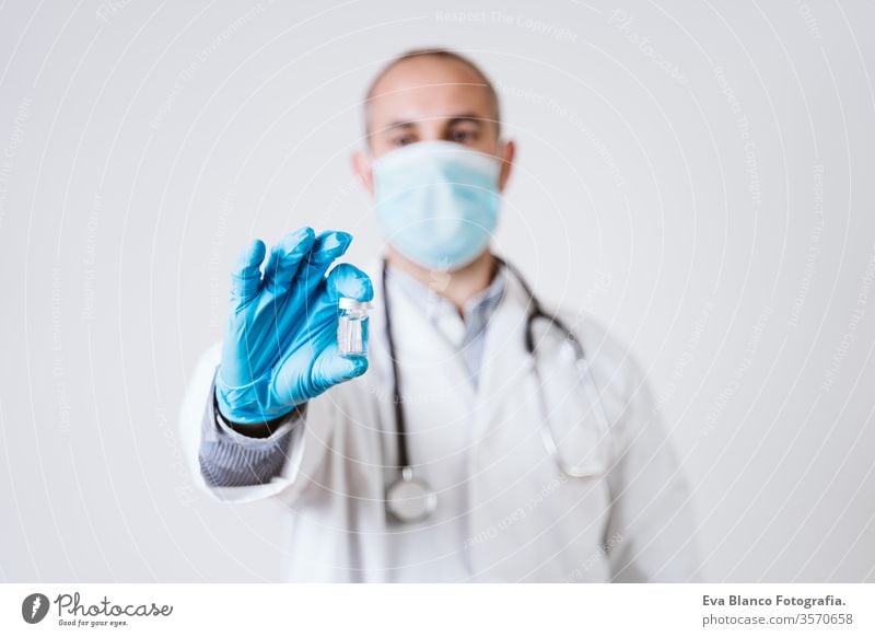 doctor man holding a vial. using protective mask and gloves during corona virus covid 2019 pandemic. Health care and medical concept syringe cod-2019 tube