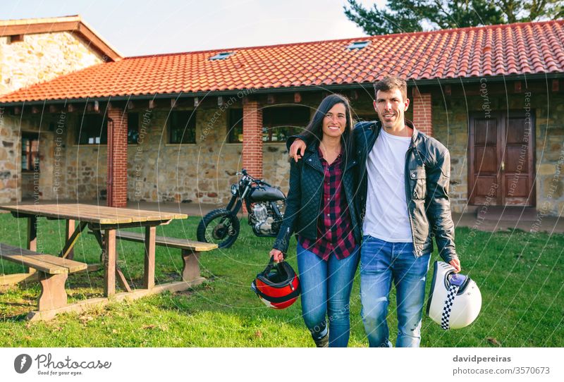Couple walking embraced and custom motorcycle attractive young couple motorbike vintage house picnic table retro vehicle biker transport fashion girlfriend