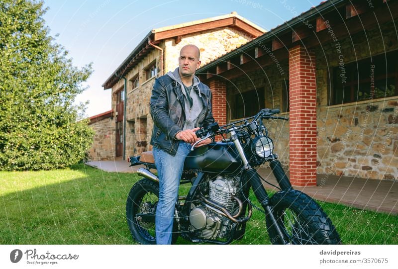 Man riding custom motorbike young man biker cafe racer posing vintage retro rider vehicle shaven head motorcycle transport fashion adult attractive one people