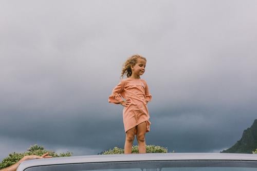 Child stands on the roof of a car and the wind blows her hair back Hawaii Gale Beach Sky Coast Clouds Colour photo Nature Wind Exterior shot Landscape Storm