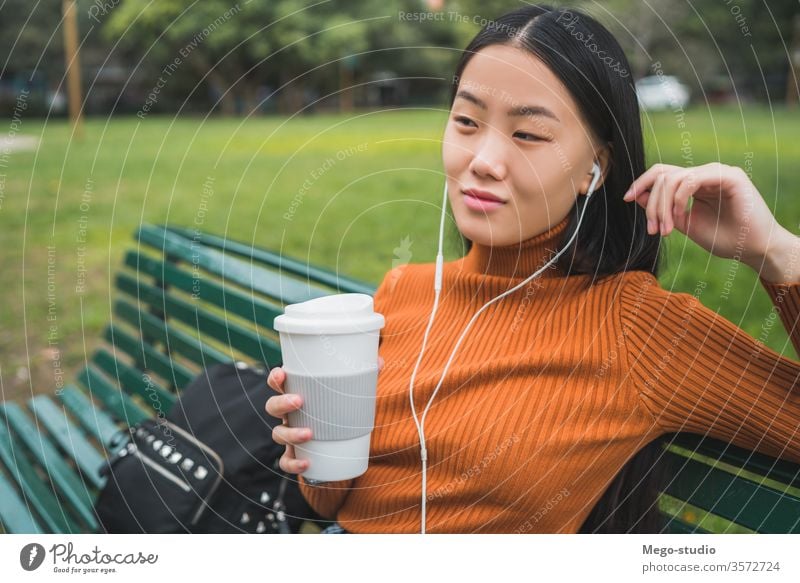Asian woman listening to music. coffee girl asian park outdoor young beautiful headphones person outside lifestyle chinese female city green people japanese