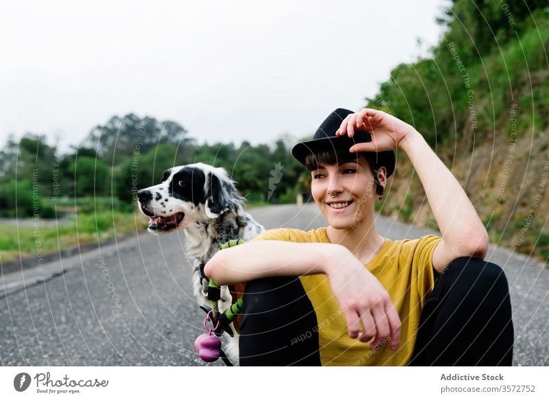 Positive young lady sitting with her dog on ground on street woman nature together hipster pet love road happy companion friend positive english setter walk