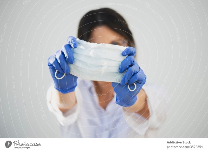 Anonymous woman holding protective mask and wearing gloves at home coronavirus show covid safety pandemic risk disease female serious outbreak infection prevent