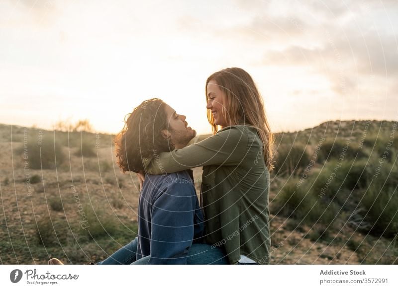 Delighted couple hugging during sunset in nature fun date love together relationship happy man woman romantic cheerful affection lift carry girlfriend boyfriend