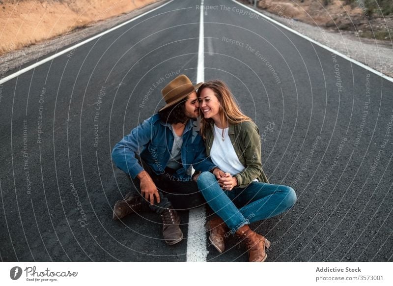 Happy couple sitting on road and touching noses smile touch nose date love countryside travel tender together man woman flirt cheerful casual happy relationship