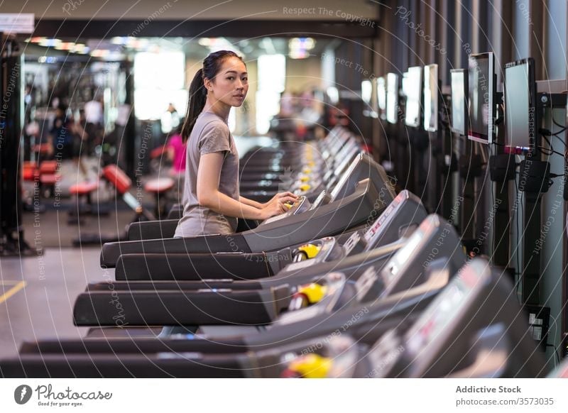 Young ethnic sportswoman running on treadmill while training in modern gym cardio exercise athlete healthy workout fitness slim young active wear wellness