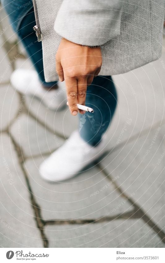 Woman smoking with cigarette in hand Smoking Cigarette Nicotine sneakers jeans out cauterizing Tobacco products Smoke Unhealthy Addiction Nicotine odour