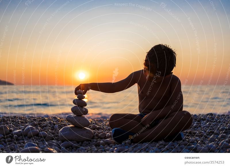 Little child playing with stones on the beach at sunset activity background balance balancing beautiful beauty boy childhood copy space family fun golden