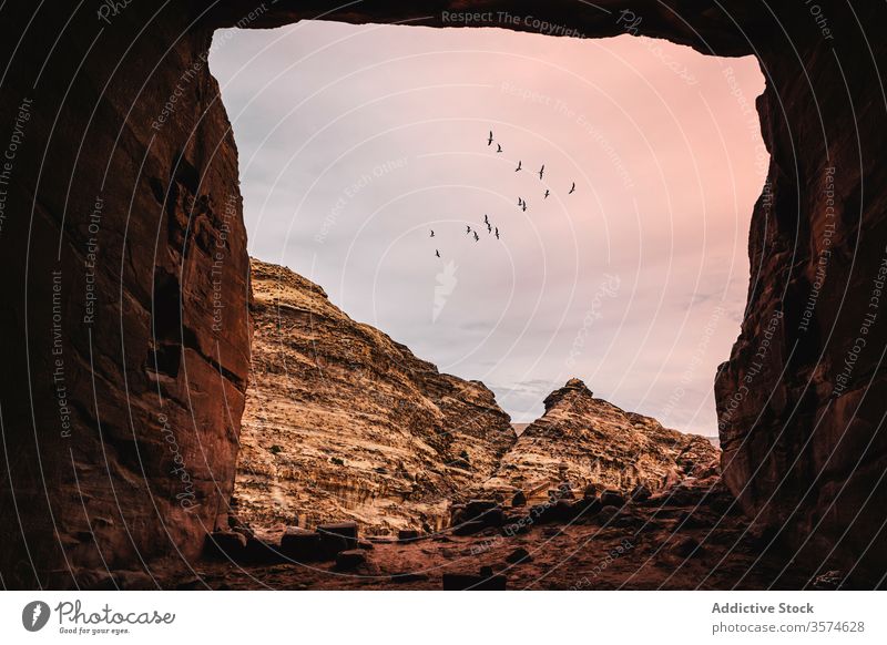 Picturesque view from cave with square entrance rocky mountain sunset cloudy sky flock bird petra jordan amazing scenic picturesque landscape nature environment