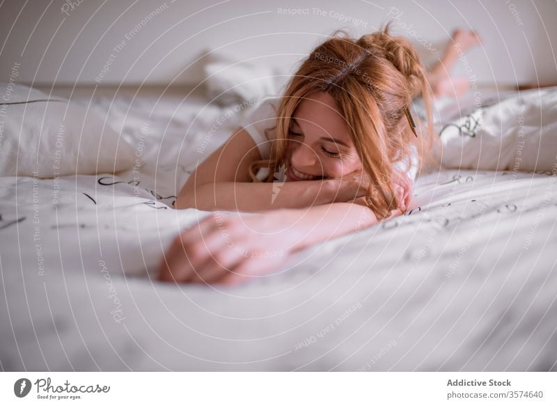 Cheerful barefoot ginger woman waking up on bed satisfied cheerful weekend rest smile lying wake up at home female happy young redhead red hair eyes closed