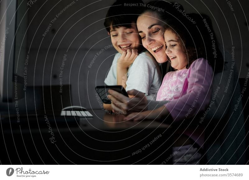 Cheerful woman with kids watching video on computer mother using smartphone together telework childcare happy cheerful home communicate gadget children mom