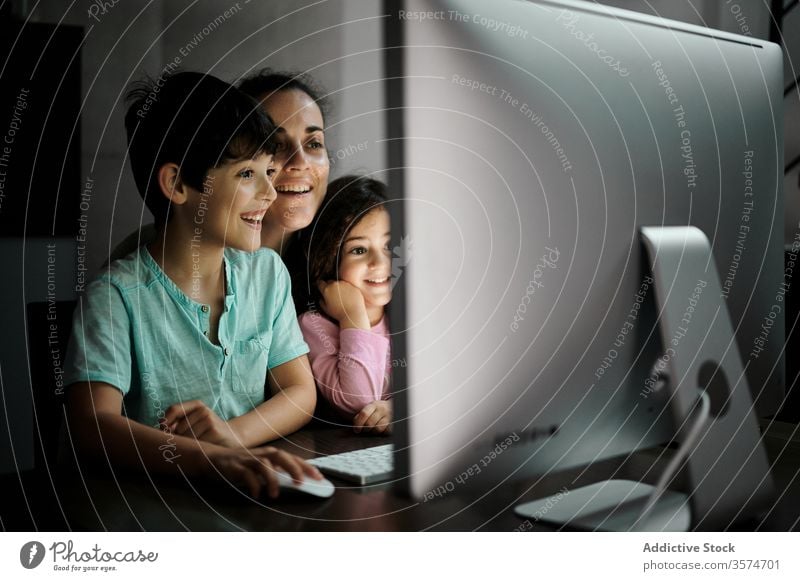Cheerful woman with kids watching video on computer mother using smartphone together telework childcare happy cheerful home communicate gadget children mom