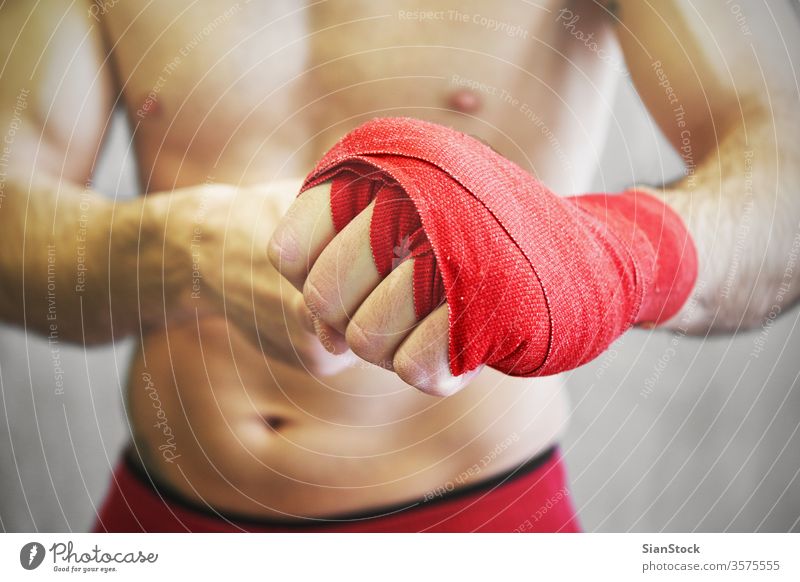 Man is wrapping hands with red boxing wraps. boxer fight man arm background wrist athlete fighter fitness strong muscular isolated sweaty white sports athletic