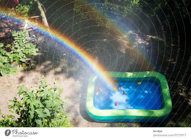 Rainbow over a paddling pool in a garden Garden Paddling pool Water Toys Drops of water spray mist Sunlight Infancy out Beautiful weather warm season Summer