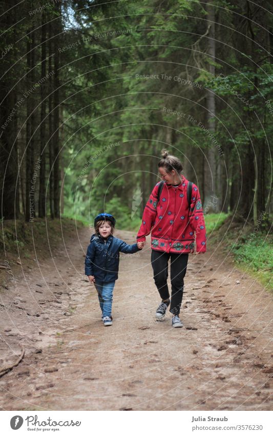 Woman walking with child in the forest Forest forest path Earth Fir cone huts Spruce forest Bike helmet Hiking stroll Walking Chignon fleece jacket Rain jacket