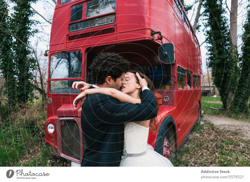 Stylish newlywed couple hugging and kissing near double decker bus red bus forest wedding embrace in love bride groom wedding day wood classy style elegant
